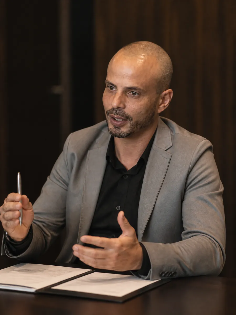 Alessandro Chaves em atendimento de consultoria, explicando um plano com a pasta de documentos aberta sobre a mesa